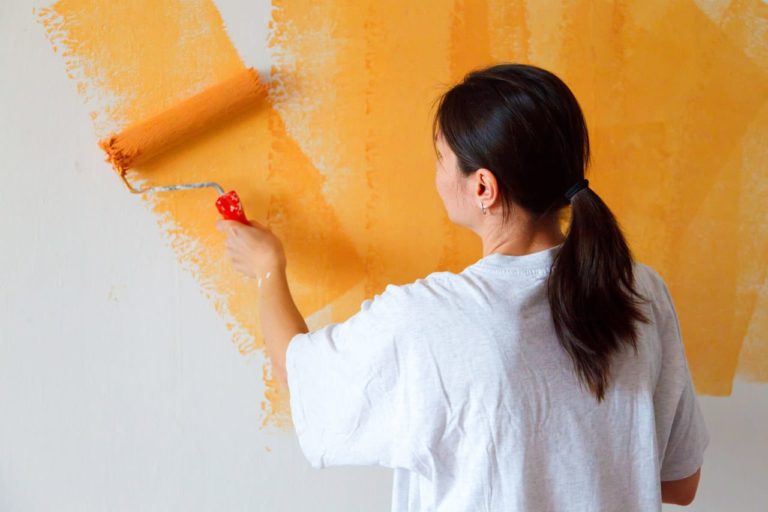 Woman painting a wall with orange paint